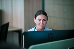 A woman, Taylor Hopkinson Offshore Wind Consultant Holly Dawson, working at her desk while wearing earphones in the company's Glasgow HQ.